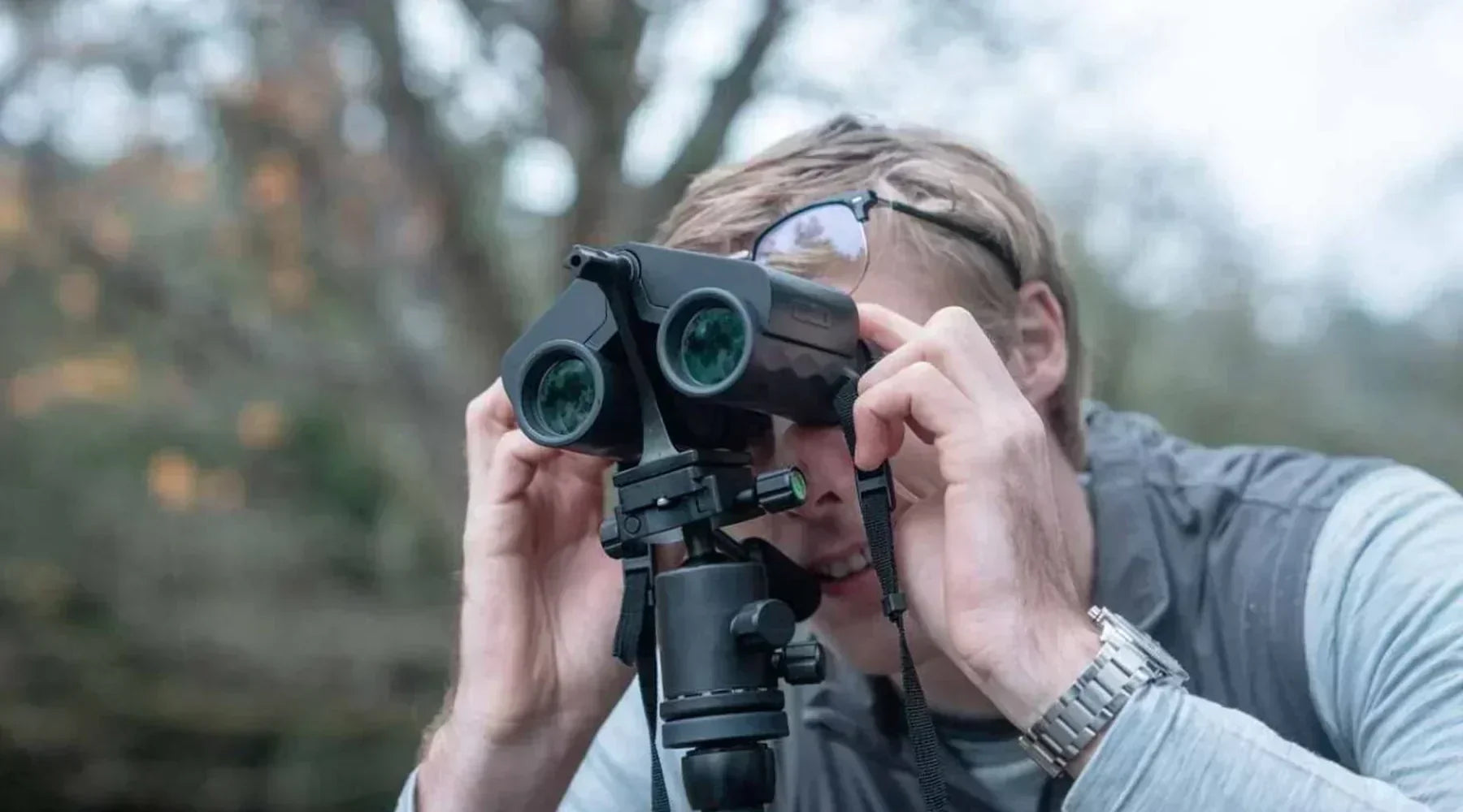 A man looking through a pair of Binoculars