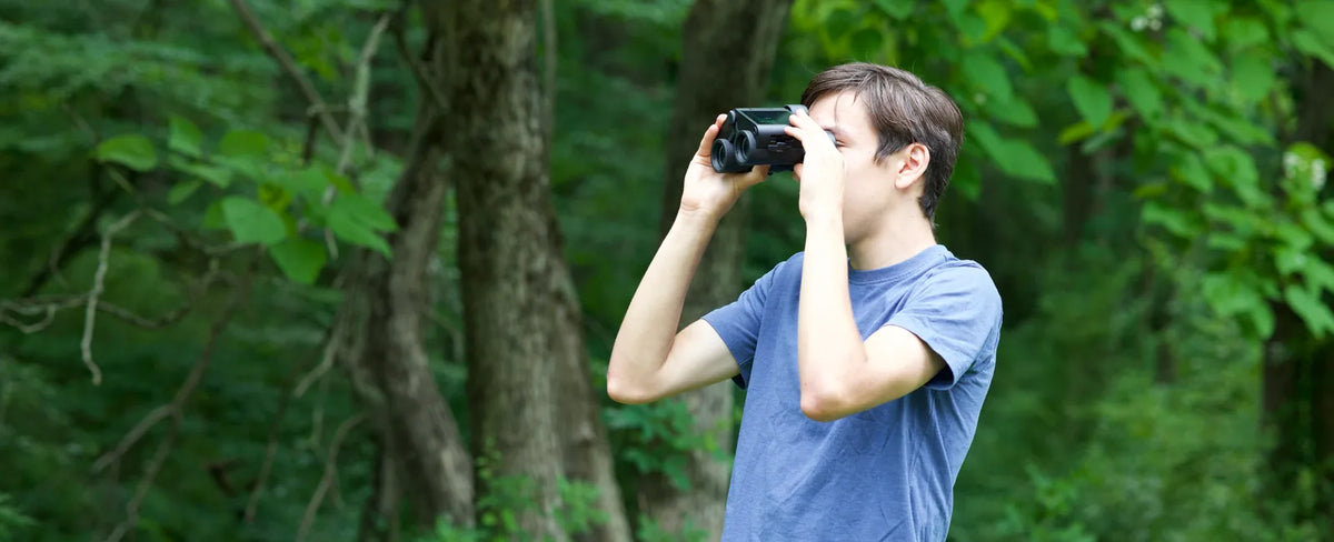 Birdwatcher using Solvia binoculars in green woodland