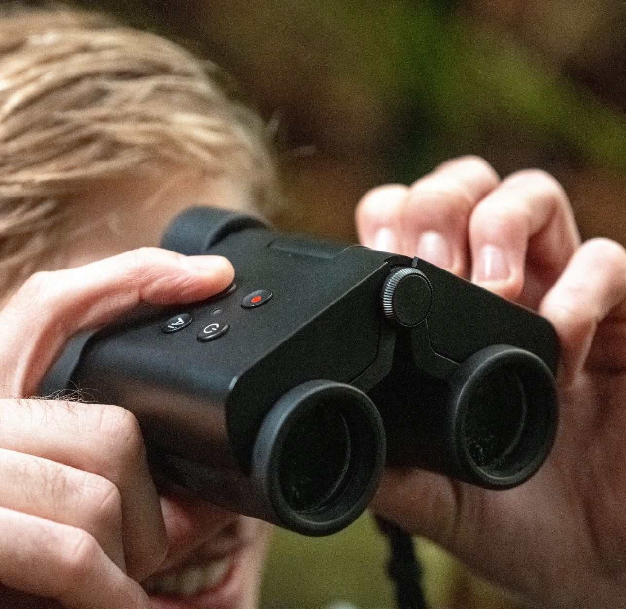 Person holding and using Solvia ED 8x32 binoculars outdoors
