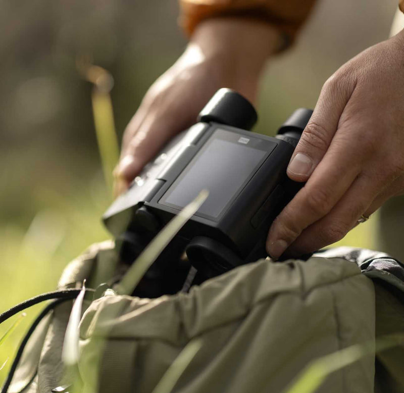 Solvia ED 8x32 compact binoculars in hand outdoors with backpack background