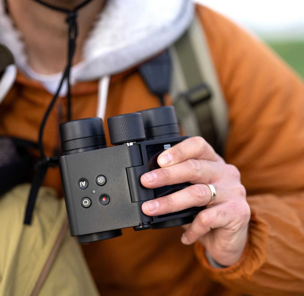 Close-up of a person holding Solvia ED 8x32 binoculars outdoors