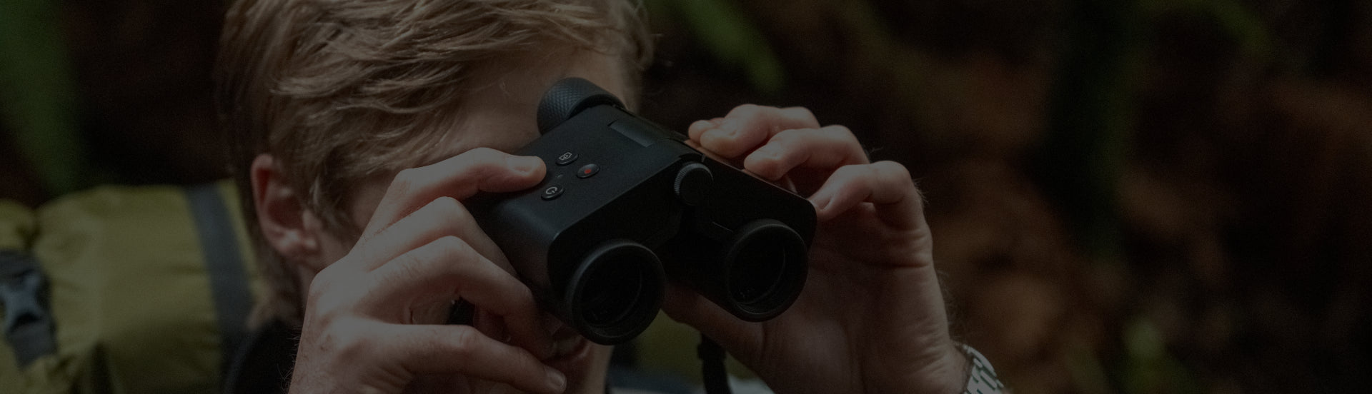 Person using binoculars with a natural background