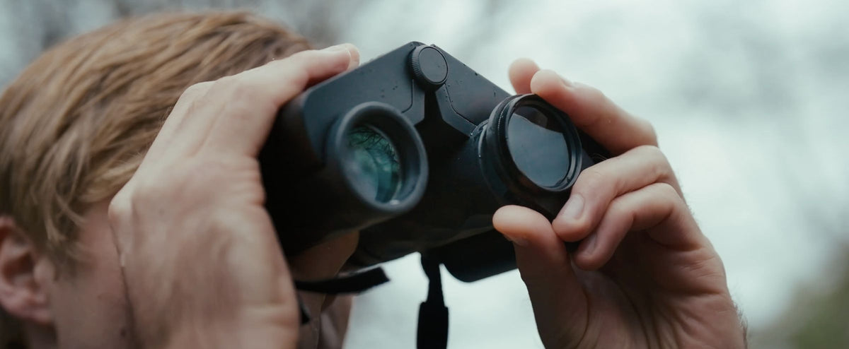 Person holding Solvia ED 8x32 binoculars with a blurred natural background